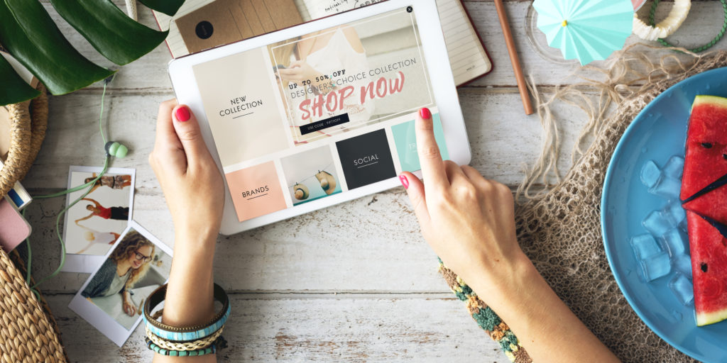 A woman's hands holding an ipad with a shopping website shown.