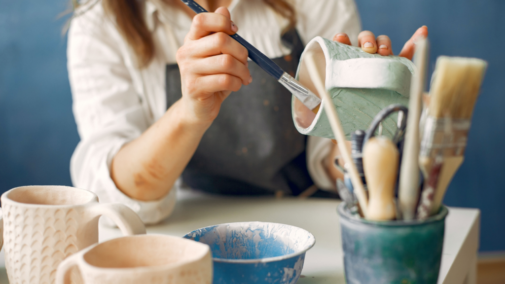A woman glazing a piece of handmade pottery