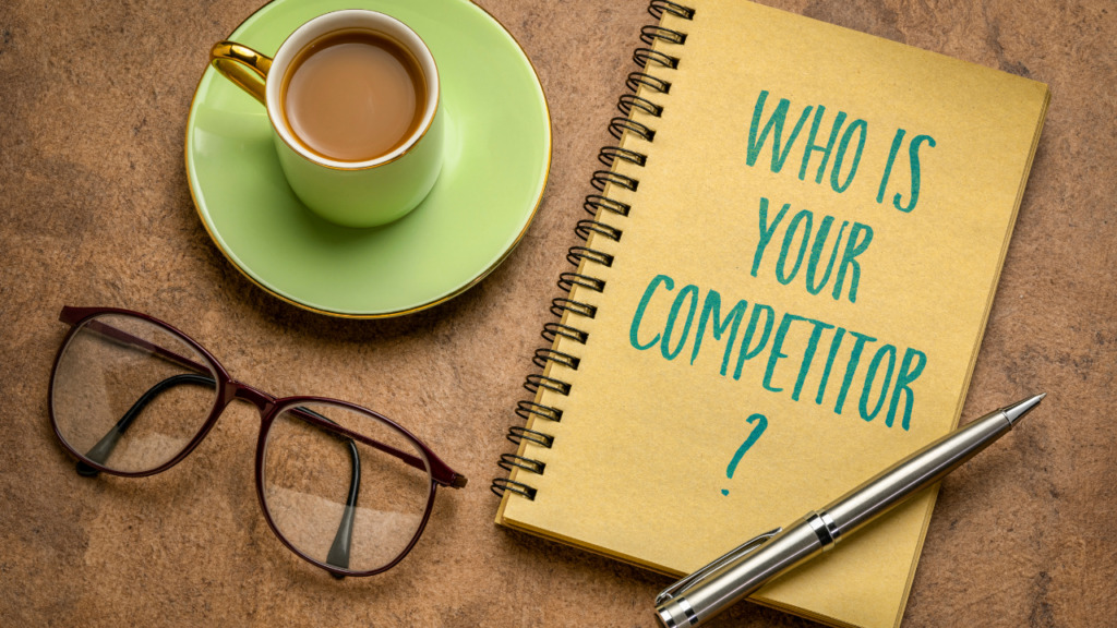 A cup of espresso and glasses next to a notebook that says, "who is your competitor?"