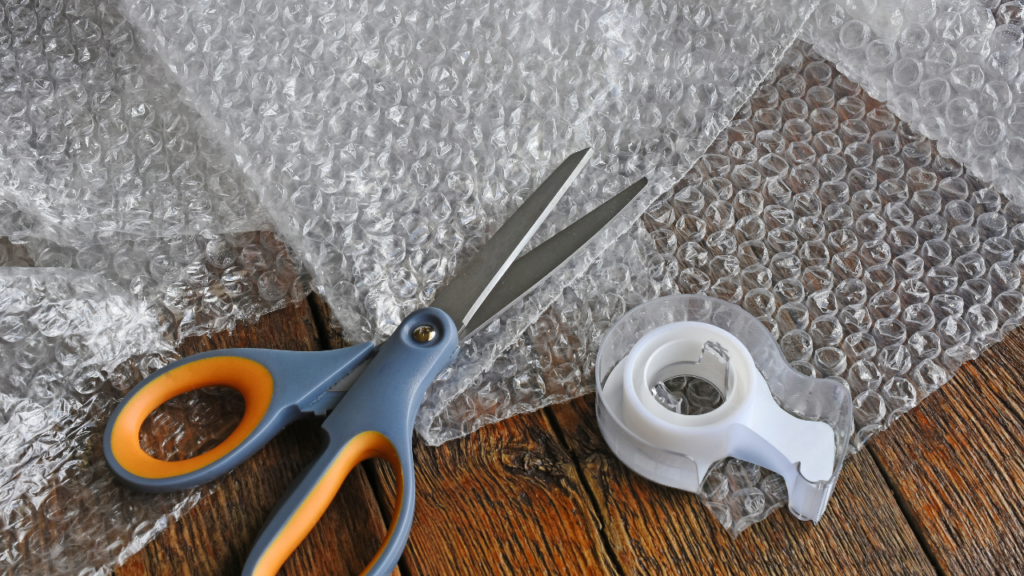 a pair of scissors, tape and bubble wrap - packing materials for shipping handmade items