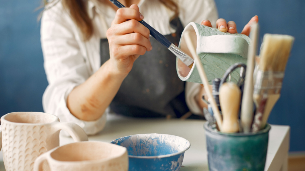 A potter glazing a ceramic mug