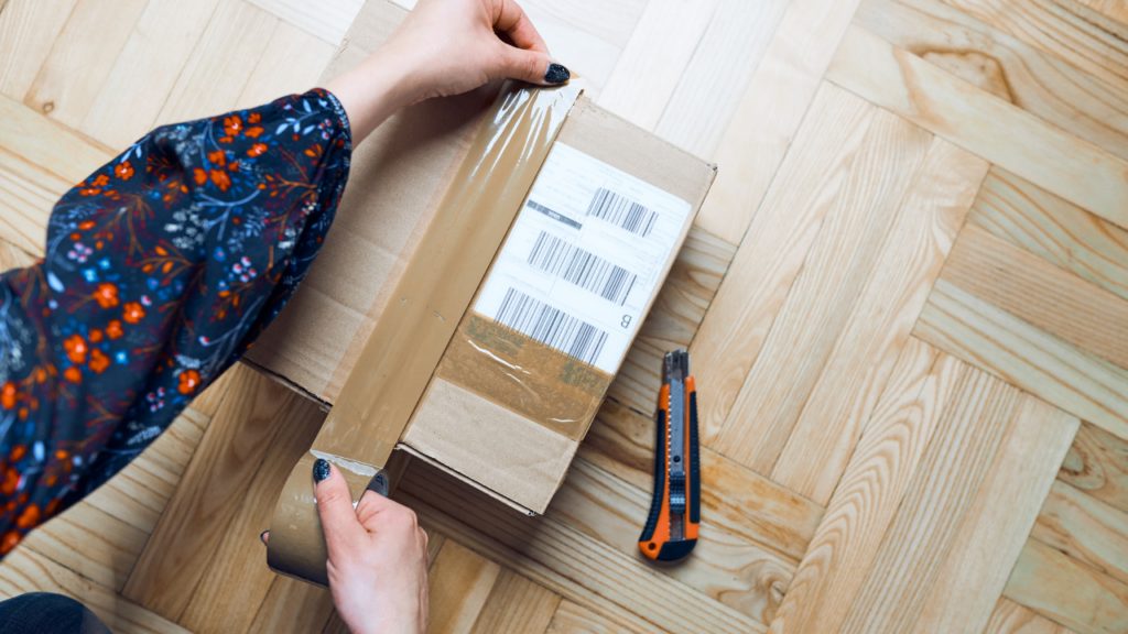 A woman packaging an order with packing tape, following shipping tips for small businesses
