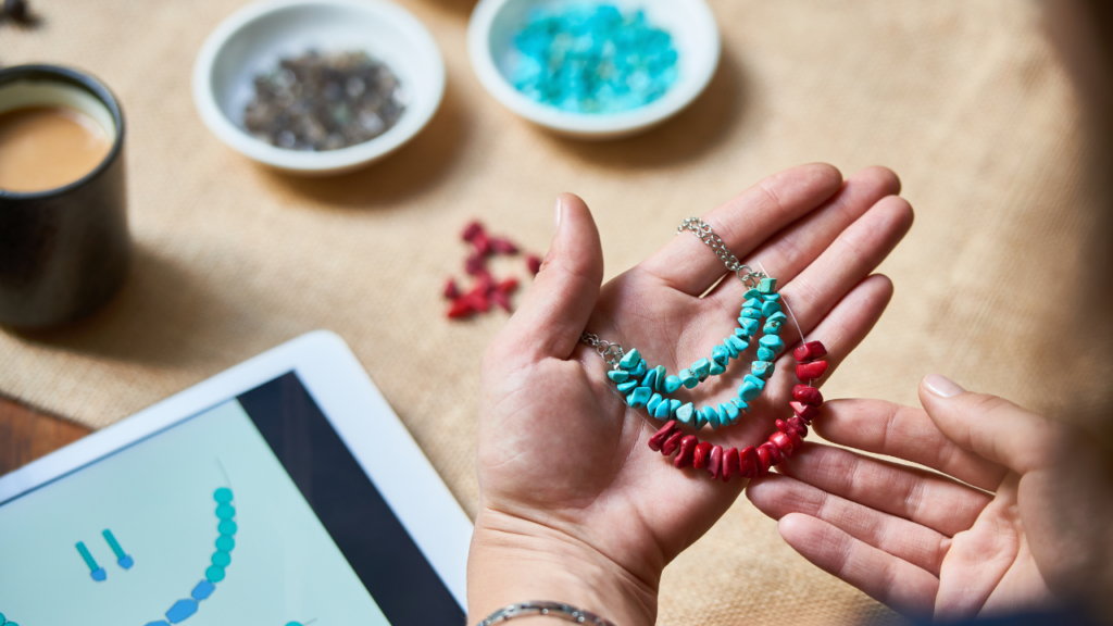 A woman refreshing her handmade brand by creating new jewelry with turquoise and red beads.