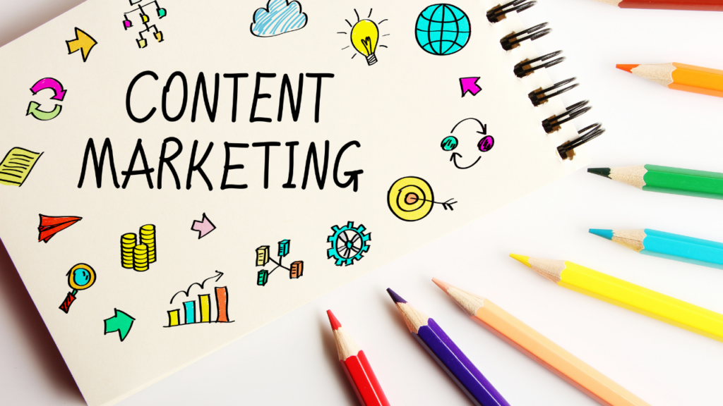the words content marketing on a pad with colorful images around them and several colored pencils next to the pad.